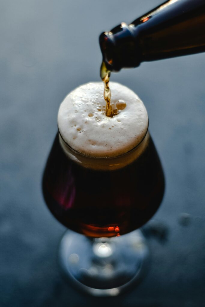 Close-up of dark beer being poured into a glass, creating a rich foam. Perfect for beverage enthusiasts.